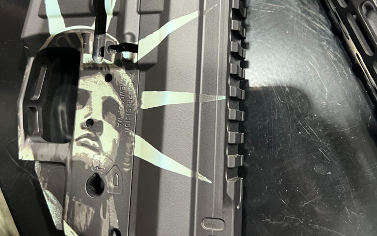 Custom Cerakote AR-15 receiver with urban camouflage pattern and clean masked lines during coating process, made simple with a firearm customization platform